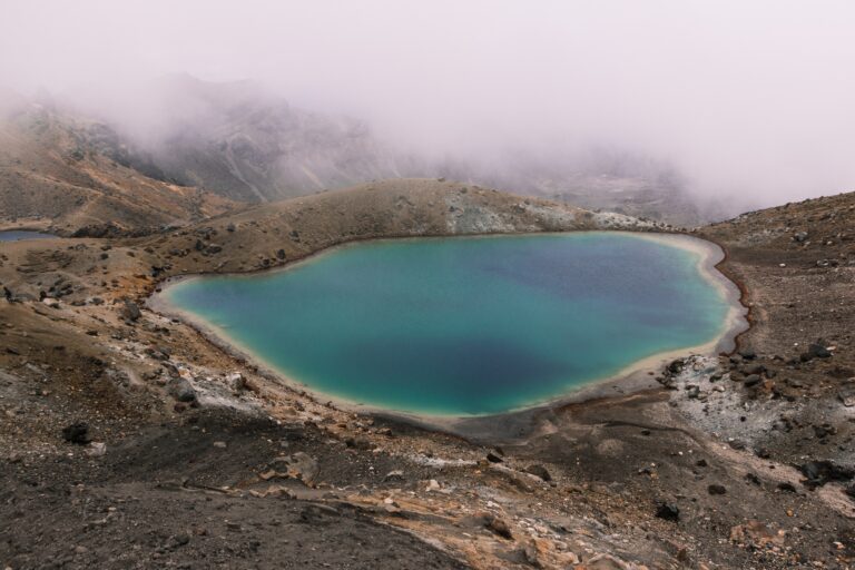 Beautiful aerial shot of a small lake in the middle of the desert near a mountain on a foggy day