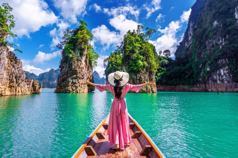 Beautiful girl standing on the boat and looking to mountains in